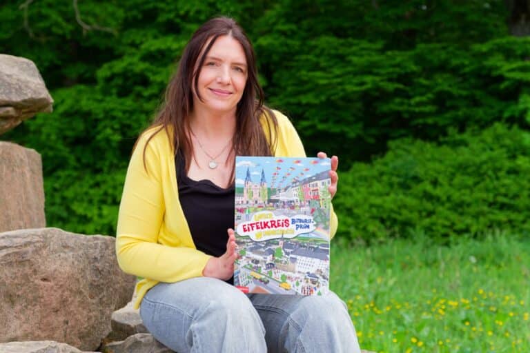 Das Eifelkreis Wimmelbuch und Loretta Englich. Frau hält Buch in der Natur.