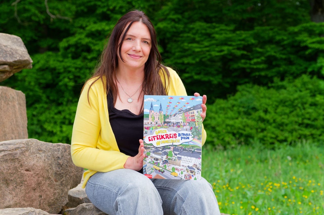 Das Eifelkreis Wimmelbuch und Loretta Englich. Frau hält Buch in der Natur.